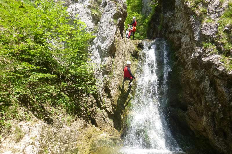 Canyoning Teilnehmer seilt durch Wasserfall ab.