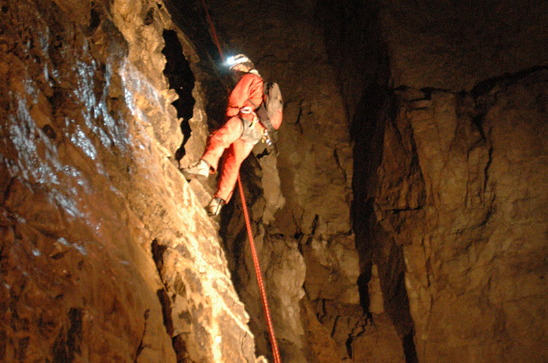 Mann beim Abseilen in der Höhle